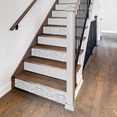 the stairs are painted white and have decorative wallpaper on each handrail, along with wood flooring