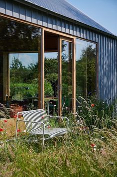 a white bench sitting in the grass next to a building with sliding glass doors on it