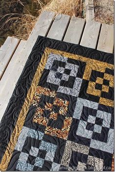 a black and gold quilt on a wooden deck