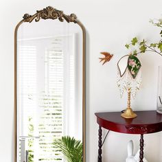 a mirror sitting on top of a table next to a plant