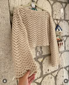 a hand holding onto a sweater hanging on a wall