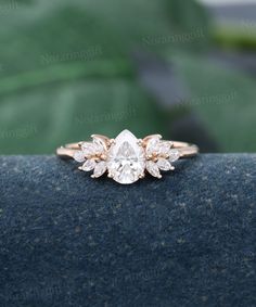 a close up view of a diamond ring on a blue surface with green leaves in the background