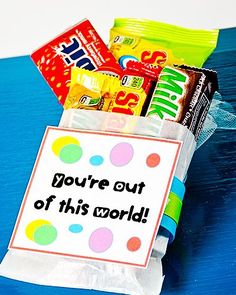 a bag filled with candy sitting on top of a blue table next to a sign that says you're out of this world