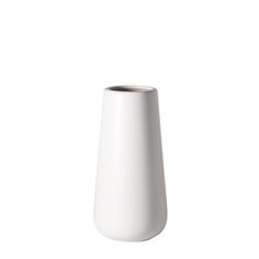 a white vase sitting on top of a white table next to a black cup in front of it