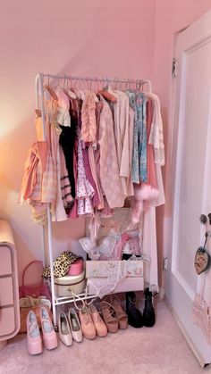 a closet filled with clothes and shoes next to a bed in a room that has pink walls