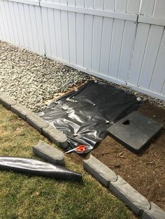 some concrete blocks laying on the ground in front of a fence and a building with white siding