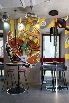 an artistic mural is on the wall in this modern dining room with bar stools