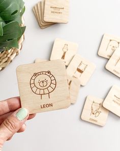 a hand holding a wooden stamp with the name leon on it next to some rubber coasters