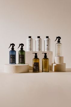 five different types of soaps and lotions on a white surface, with one being used as a dispenser