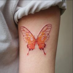 an orange butterfly tattoo on the right side of the leg, with wings spread out