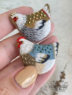 two small birds sitting on top of each other in someone's fingernails