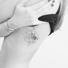 a woman with a tattoo on her stomach holding her hand up to her chest and looking at the camera