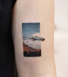 a woman's arm with a car on it and clouds in the sky behind her