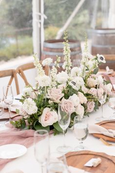 a table set with flowers and wine glasses for a wedding reception at the vineyard house