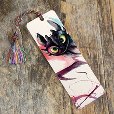 a phone case with an image of a cat and tassels on it sitting on a wooden surface