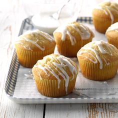 several muffins with white icing on a tray