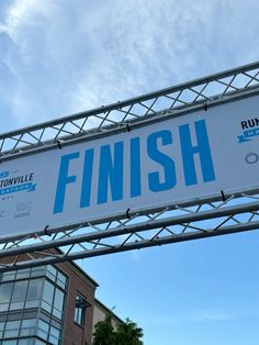 a sign that says finish hanging from a metal frame in front of a brick building