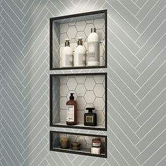 two shelves with bottles and soaps on them against a wall in a bathroom that has chevroned walls