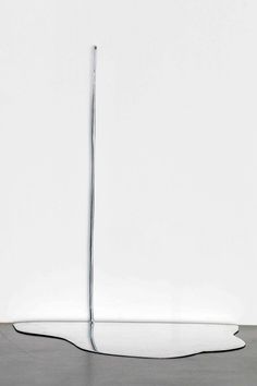 an abstract sculpture is shown in front of a white wall and floor with a long metal pole sticking out of it