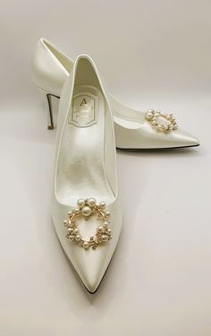 a pair of white shoes with pearls on them