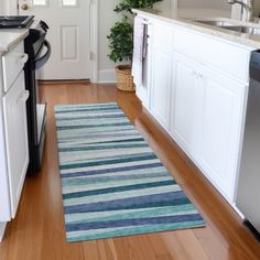 a blue and green rug in a kitchen next to a dishwasher, refrigerator and sink