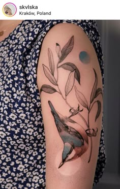 a woman's arm with a bird and leaves tattoo on the left side of her arm