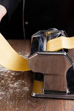 a person using a pair of scissors to cut paper on a piece of wooden table