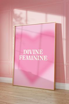 a pink poster with the words divine feminine on it in front of a wooden floor