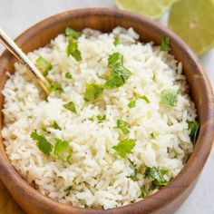 a wooden bowl filled with white rice and garnished with cilantro leaves