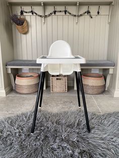 a white high chair sitting on top of a gray rug in front of a bench