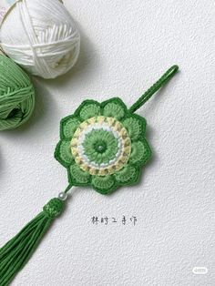 two balls of yarn are next to each other and one has a green flower on it