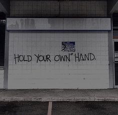 graffiti on the side of a building that says hold your own hand written in black