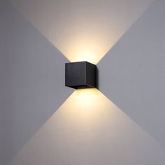 a wall mounted light on the side of a white wall in a room with grey walls