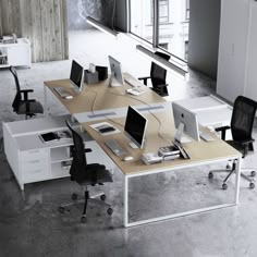 an office with multiple desks and computers on them in the middle of a room