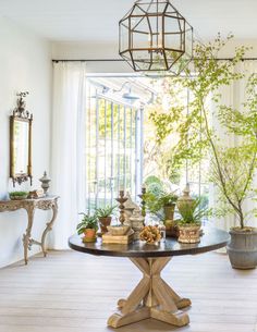 a table with potted plants on it in front of an open door and window