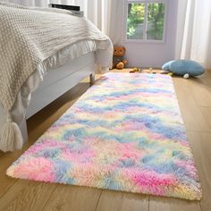 a colorful rug on the floor in a room with a bed and window behind it