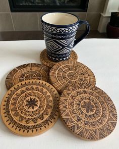 four wooden coasters sitting on top of a table next to a cup and fire place