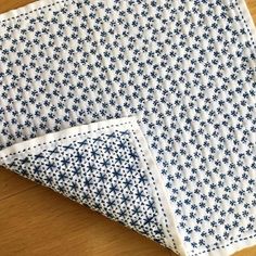 two blue and white napkins sitting on top of a wooden table