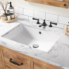 a bathroom sink sitting under a mirror next to a counter top with soap and toothbrushes on it