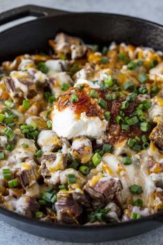 a casserole dish with meat, cheese and green onions on it's side