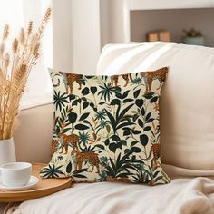 a pillow on a couch next to a cup and plate with some plants in it