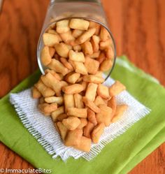 a glass jar filled with small pieces of food on top of a green napkin next to a wooden table