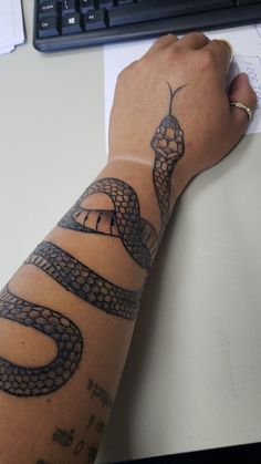 a person's arm with a snake tattoo on it