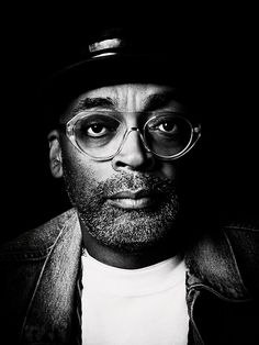 a black and white photo of a man wearing glasses, a hat, and a jacket