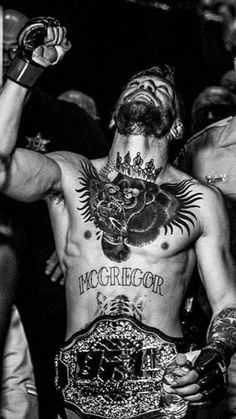 a man with tattoos on his chest standing in the middle of a group of people