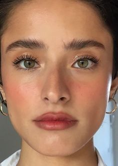 a close up of a person with large hoop earrings on her head and green eyes