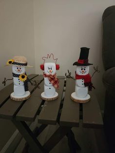 three snowmen sitting on top of a wooden table