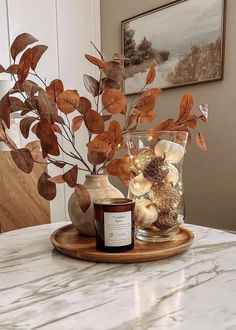 a table with a candle and some leaves in it on top of a wooden tray