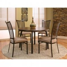 a round table with four chairs and a vase on top of it in front of a brick wall