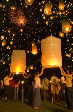 many people are holding lanterns in the air